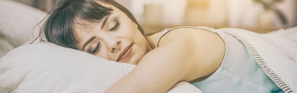young smiling woman sleeping on puffy pillow