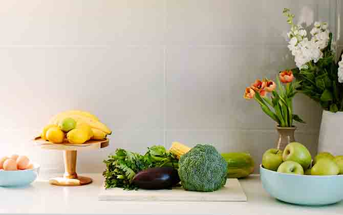 Fresh fruit, vegetables, eggs and flowers on a kitchen bench