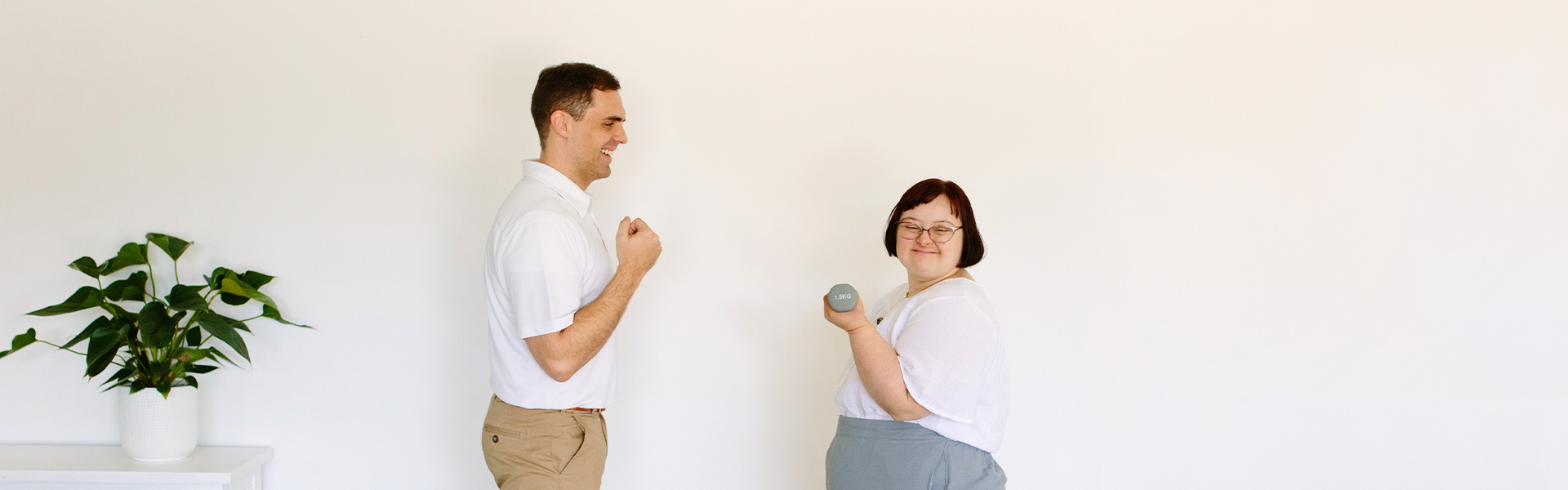 Physiotherapy session with client holding hand weight smiling at camera and physio smiling at client