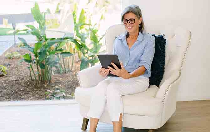 Lady sitting on chair and smiling at an ipad screen